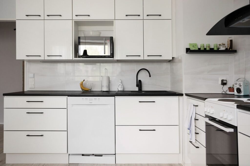 Cocina blanca moderna y elegante con electrodomésticos, que exhibe diseño de interiores contemporáneo.