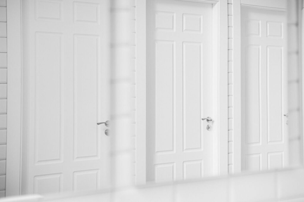 Puertas blancas limpias y simples con manijas, reflejándose en un espejo para una estética minimalista.