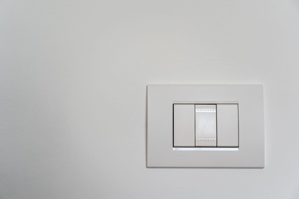 Primer plano de un interruptor de luz moderno en blanco sobre una pared limpia.