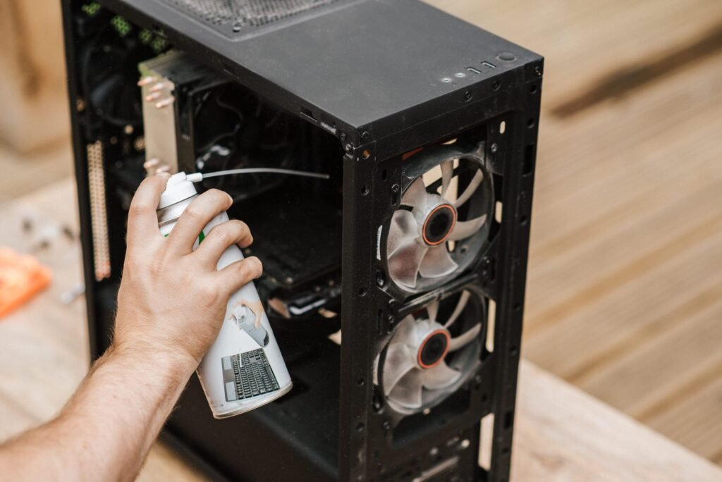 Una persona utilizando aire comprimido para limpiar una caja de computadora, enfocándose en la eliminación de polvo.