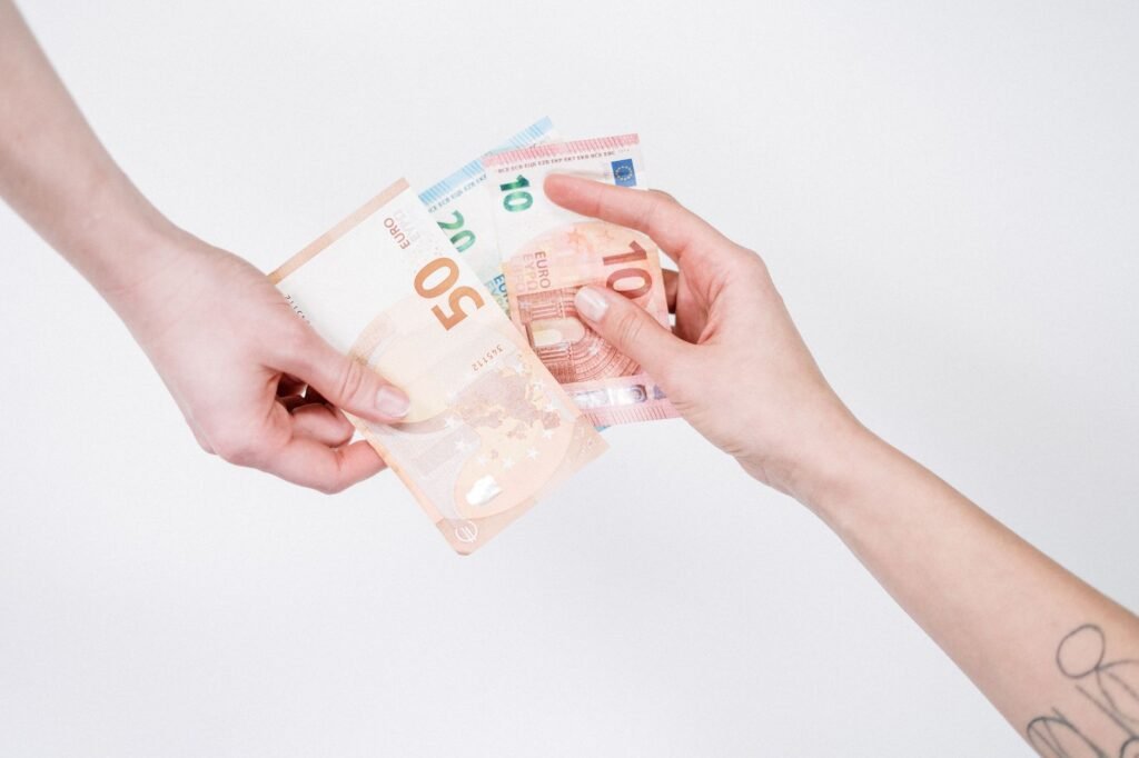Primer plano de manos intercambiando billetes de euro, simbolizando transacciones financieras y cambio de moneda.