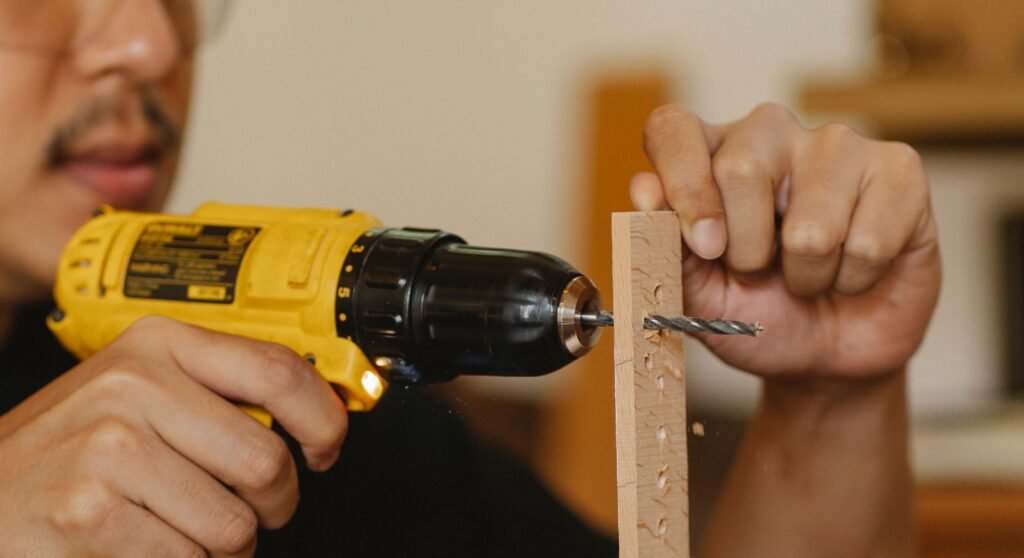 Un artesano utilizando un taladro amarillo para crear agujeros en una tabla de madera en el interior.