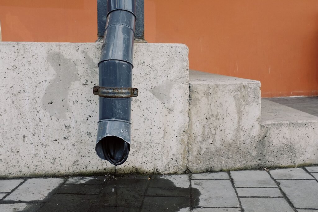 Primer plano de una escalera de concreto industrial y tubo de desagüe en un entorno urbano.