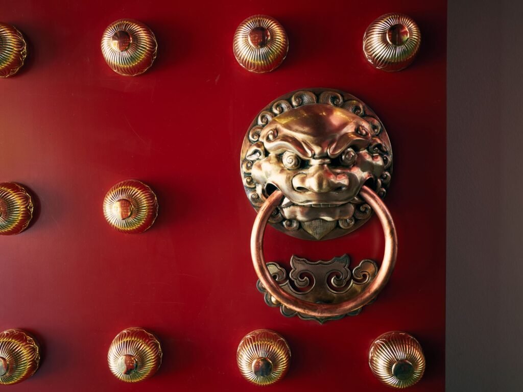 Puerta china roja tradicional con un llamador de león de latón ornamentado.