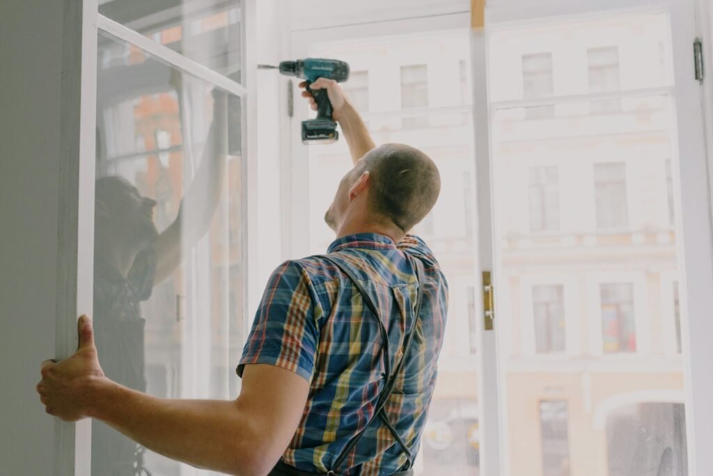 Hombre instalando ventana en interiores con un taladro, centrado en la renovación del hogar.