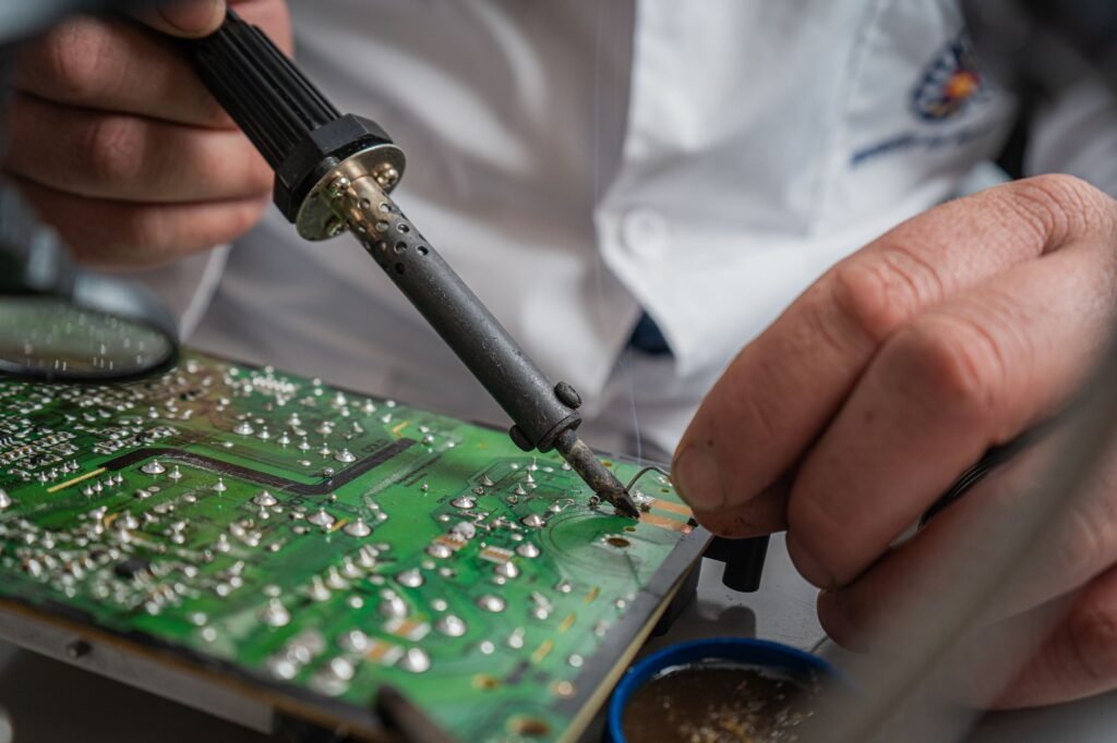 Técnico realizando soldadura de precisión en una placa de circuito impreso para la reparación de aparatos electrónicos.