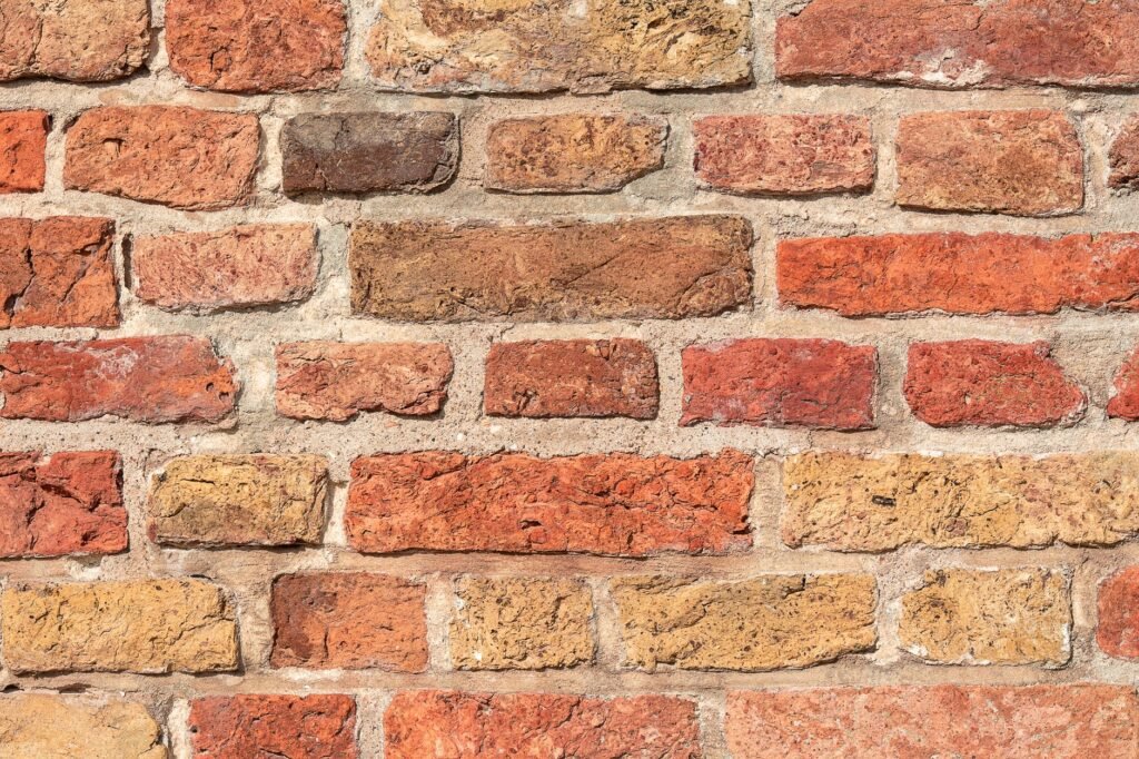 Imagen detallada de una textura de pared de ladrillos ásperos y multicolores para fondos o diseño.
