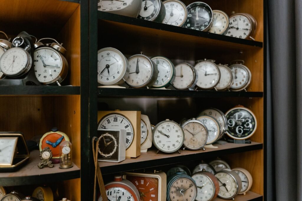 Una variedad de despertadores vintage exhibidos en estantes de madera, evocando nostalgia.