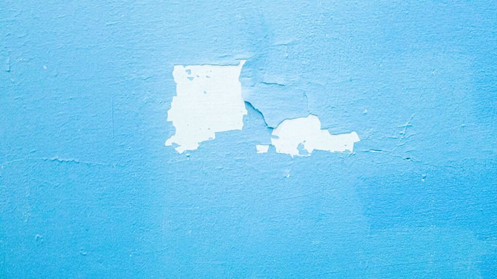 Primer plano de una pared azul texturizada con pintura descascarada que revela capas debajo.