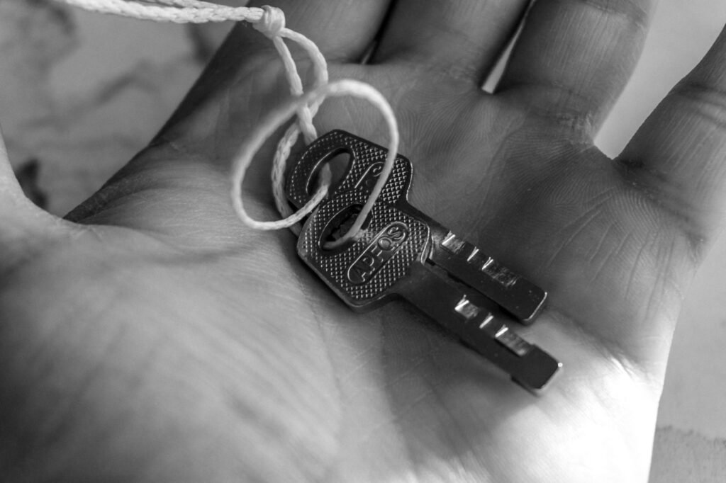 Fotografía detallada en blanco y negro de unas llaves sostenidas en una mano, que resalta la textura y los detalles.