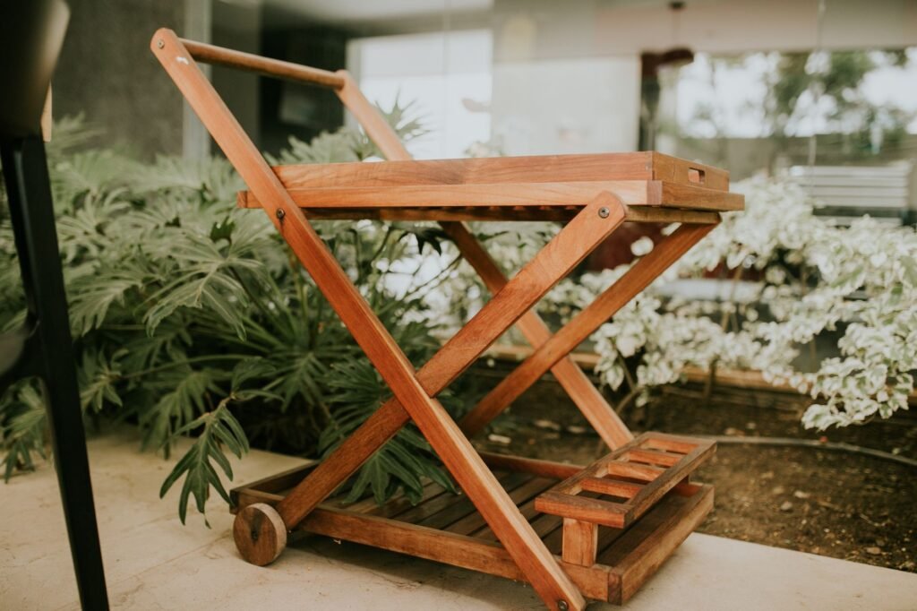 Un elegante carrito de servicio de madera colocado en medio de una exuberante vegetación en un entorno interior moderno.